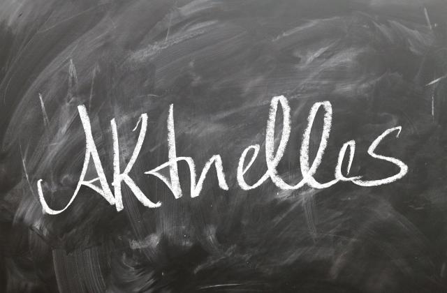 Das Foto zeigt eine graue Tafel mit dem weißen Schriftzug Aktuelles.